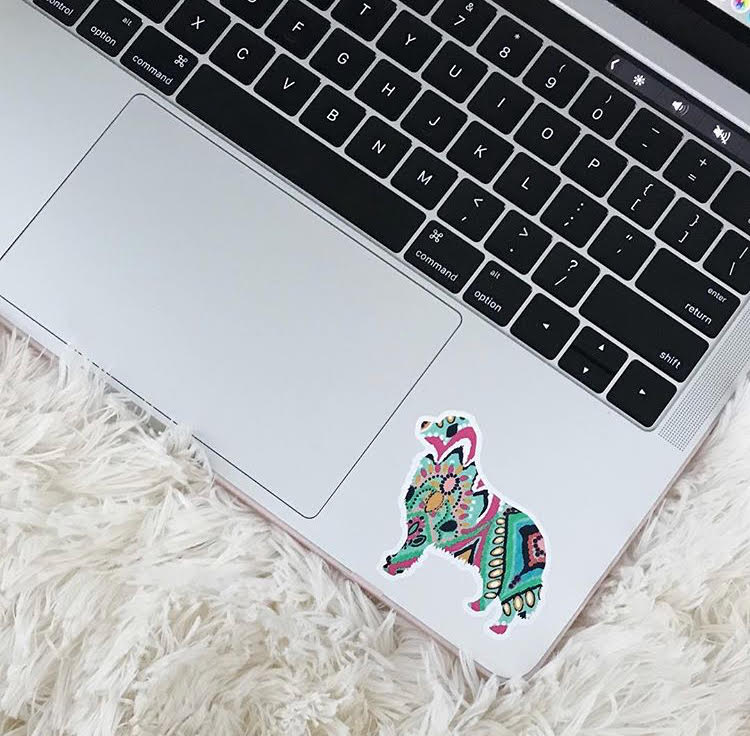 Laptop on a white blanket with a golden retriever sticker beside the track pad